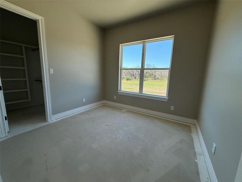 Unfurnished bedroom with a walk in closet and unfinished concrete floors