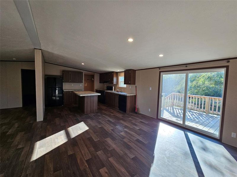 Kitchen with light countertops, dark brown cabinets, dark wood-style floors, vaulted ceiling, and black appliances Kitchen with light countertops, dark brown cabinets, dark wood-style floors, vaulted ceiling, and black appliances