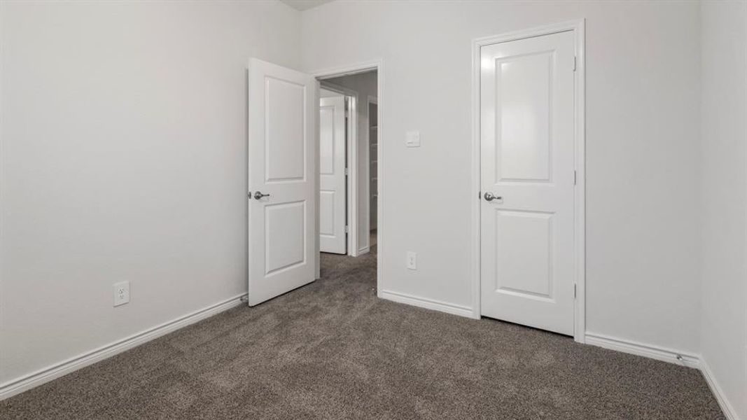 Unfurnished bedroom with dark colored carpet and baseboards
