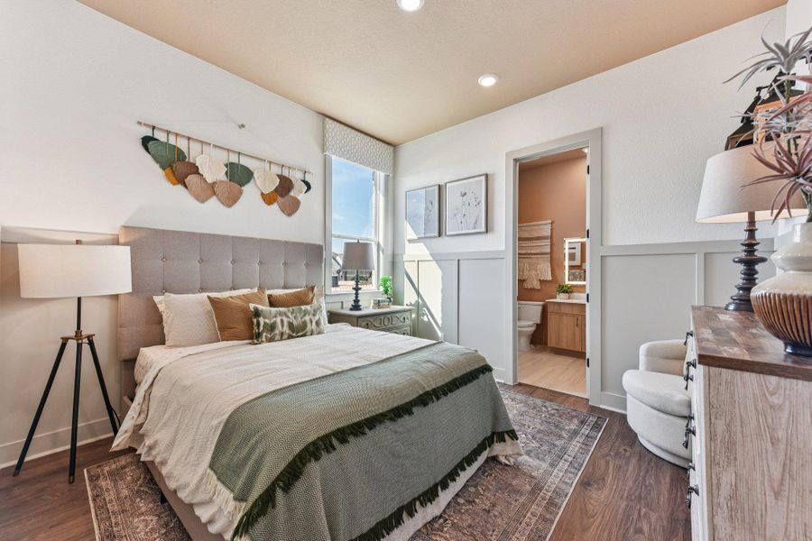 Rich wood-look flooring and custom wall paneling define this comfortable space with an attached bathroom.