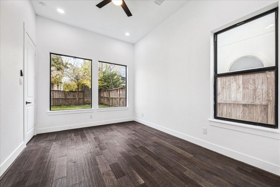 The downstairs bedroom features large windows framing the pool-size backyard, blending indoor comfort with the beauty of outdoor space.