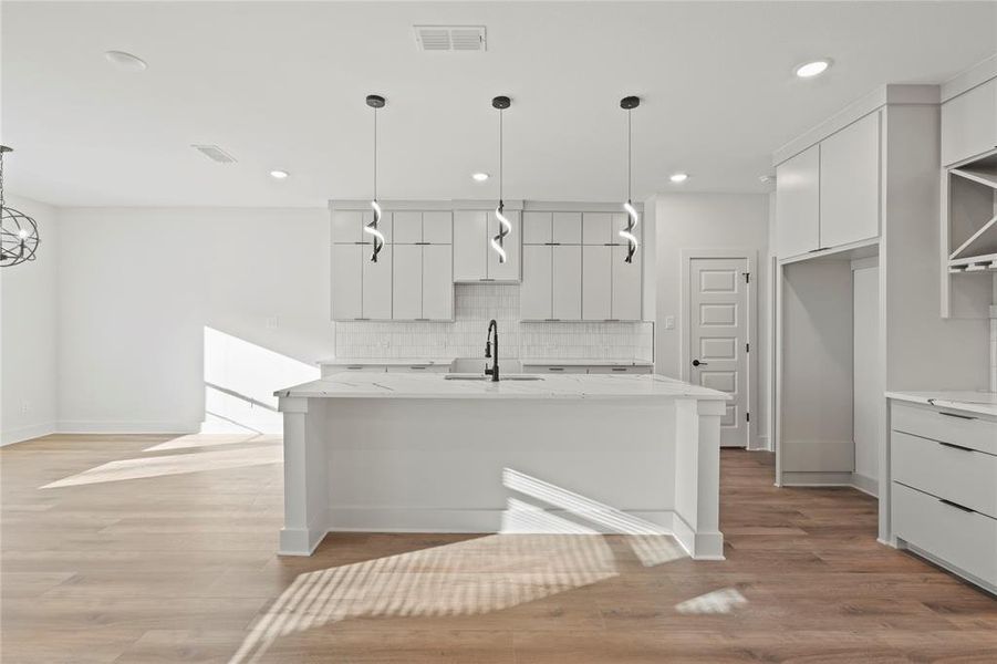 Kitchen with visible vents, white cabinets, modern cabinets, a sink, and backsplash