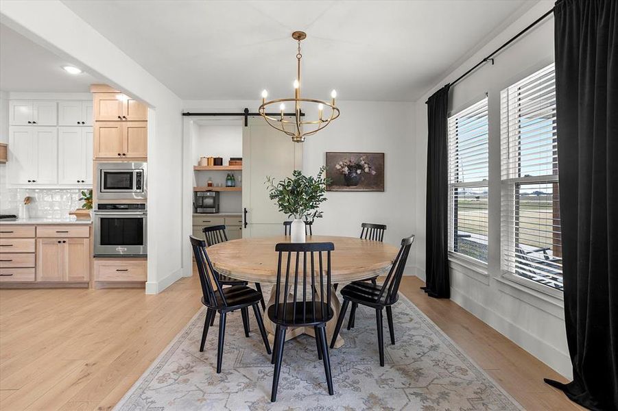 Dining space featuring light wood-type flooring, a wealth of natural light, and an inviting chandelier