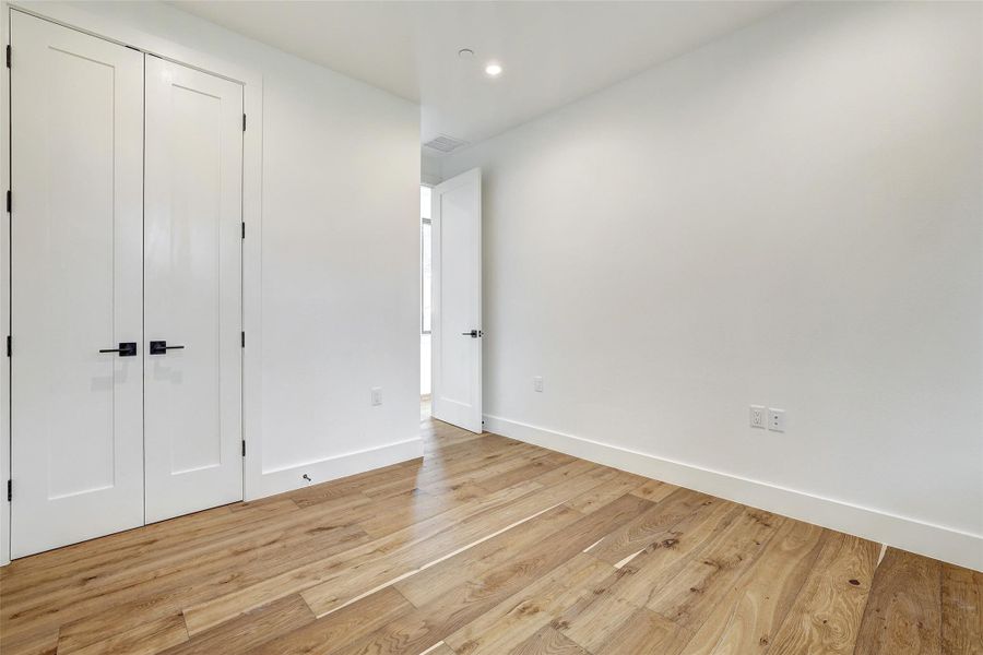 Unfurnished bedroom with light wood finished floors, a closet, and recessed lighting Unfurnished bedroom with light wood finished floors, a closet, and recessed lighting