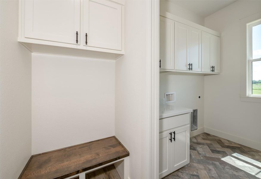 Laundry room with cabinet space, washer hookup, electric dryer hookup, and stone finish flooring