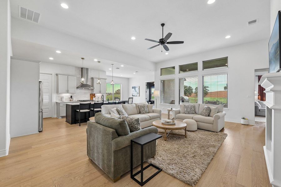 Open-concept living area featuring light wood-finish flooring, recessed lighting, and a contemporary ceiling fan