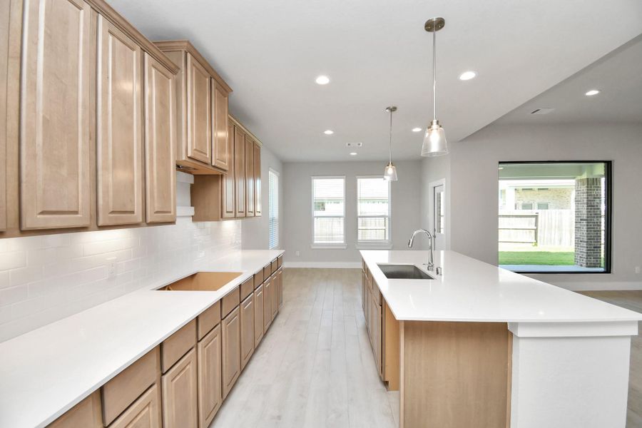 The kitchen is a culinary haven, featuring granite countertops, a tile backsplash, stainless steel appliances, 42” upper cabinets, and undercabinet lighting. Sample photo of completed home with similar floor plan. Actual colors and selections may vary. The kitchen is a culinary haven, featuring granite countertops, a tile backsplash, stainless steel appliances, 42” upper cabinets, and undercabinet lighting. Sample photo of completed home with similar floor plan. Actual colors and selections may vary.