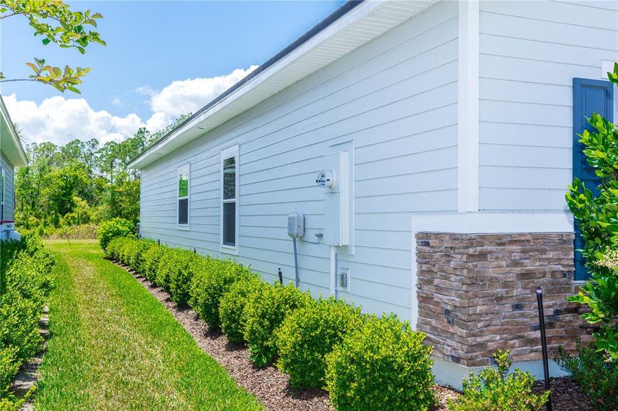 Side of home with trimmed hedges