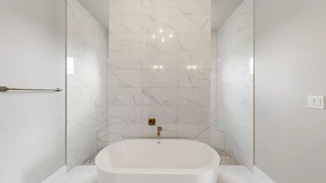 Full bath with a freestanding tub and marble finish floors