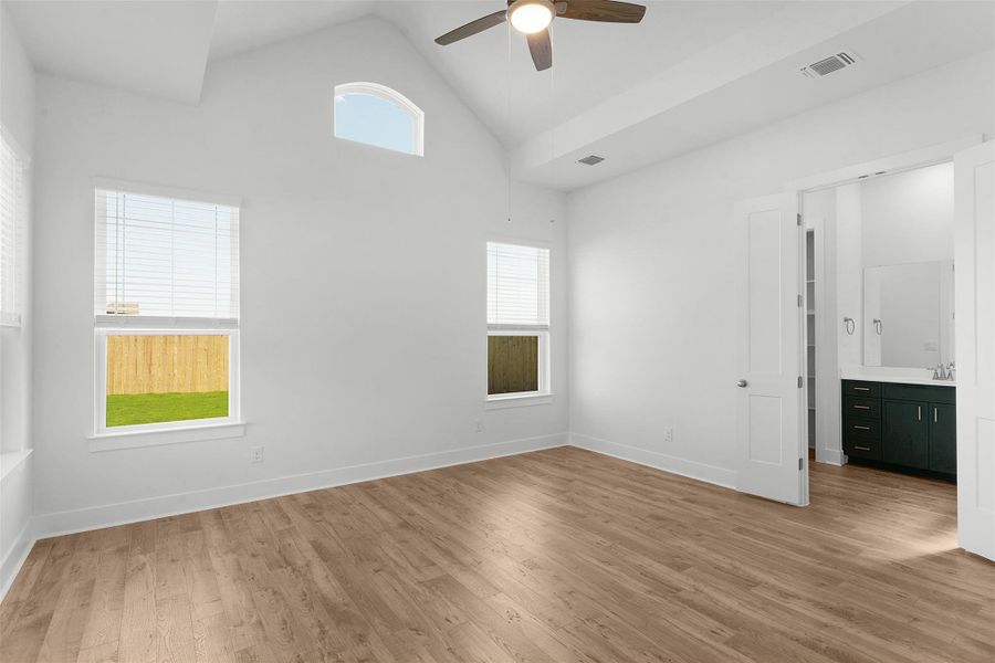 Lofty ceilings and generous windows create an airy, naturally illuminated primary bedroom.