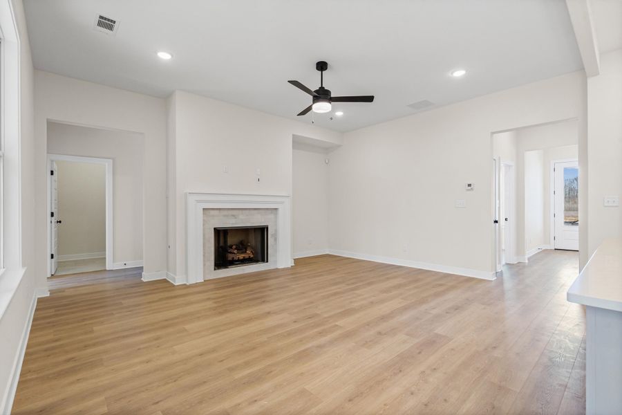 Unfurnished living room with ceiling fan, light wood-style floors, a fireplace, and recessed lighting Unfurnished living room with ceiling fan, light wood-style floors, a fireplace, and recessed lighting