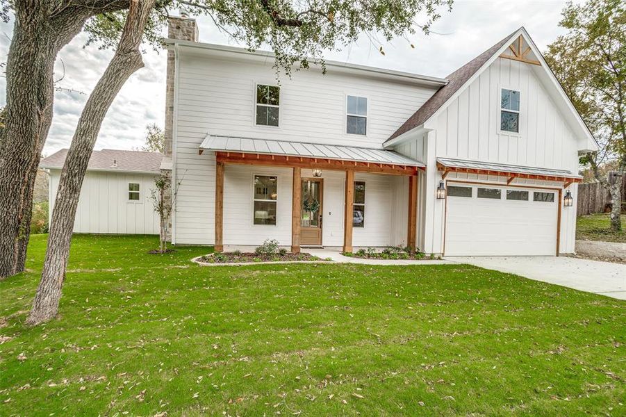 Modern inspired farmhouse with a front lawn, a porch, and a garage