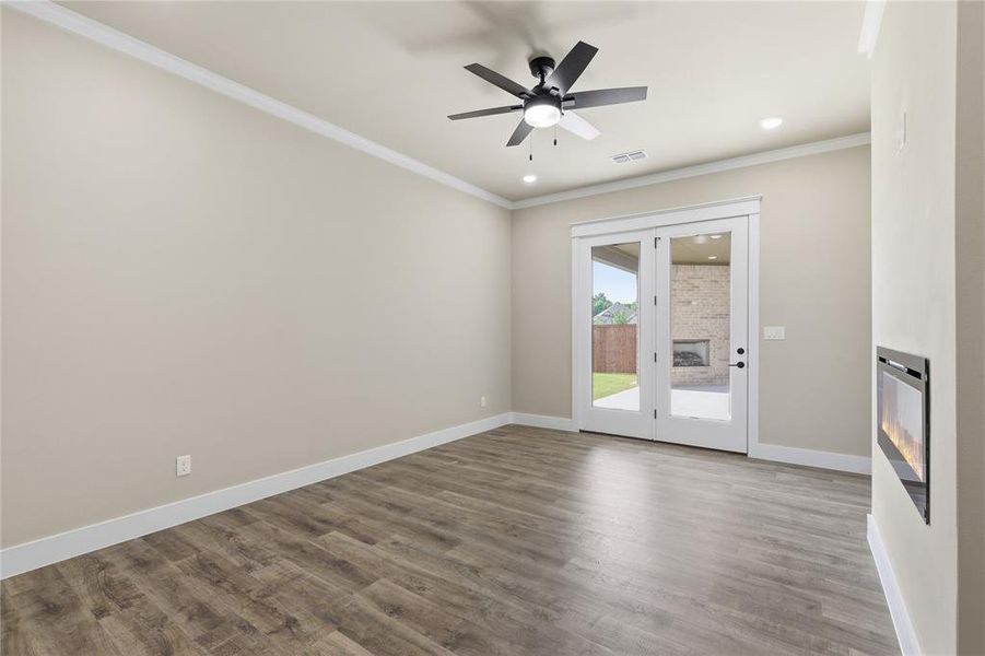 Bright interior with wood-finish flooring, crown molding, and a ceiling fan with integrated lighting