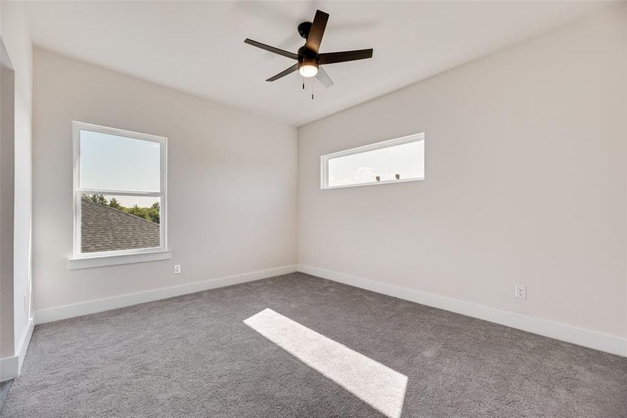 Unfurnished room featuring light colored carpet, plenty of natural light, and ceiling fan Unfurnished room featuring light colored carpet, plenty of natural light, and ceiling fan