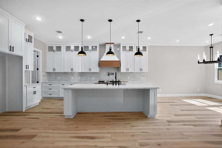 The chef’s dream kitchen features an oversized granite island, six burner range with grill and double oven, stainless steel dishwasher and microwave, farm sink and under cabinet lighting