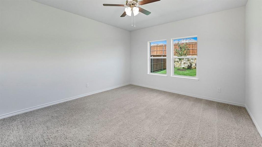 Carpeted empty room featuring baseboards and a ceiling fan