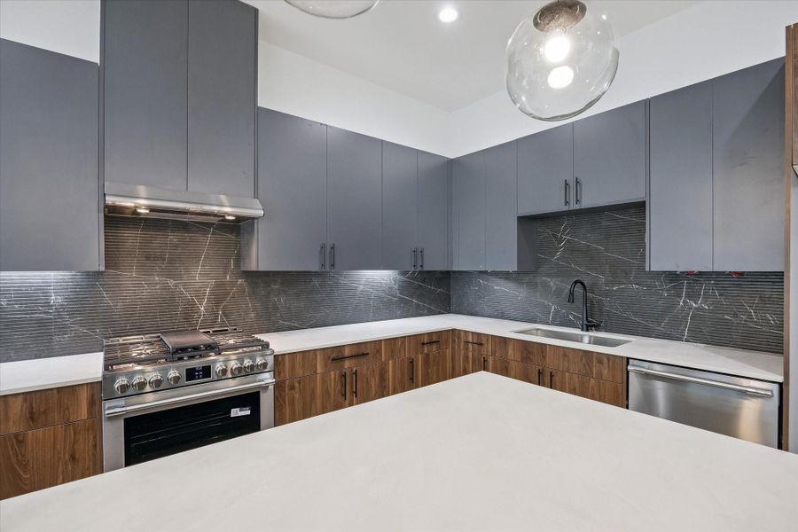 Gas range, vent hood, and backsplash detail for a refined kitchen finish