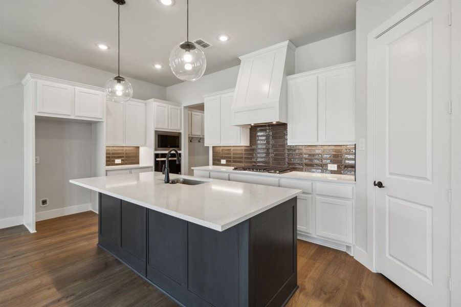 Kitchen featuring custom exhaust hood, white cabinets, stainless steel appliances, and sink