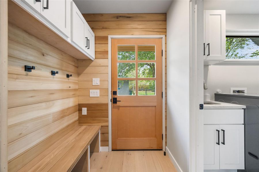 Mudroom with wooden walls, plenty of natural light, and light wood-type flooring