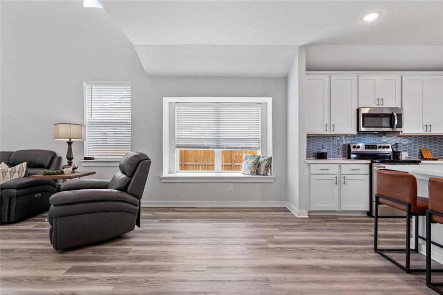Kitchen featuring stainless steel appliances, vaulted ceiling, white cabinetry, light countertops, and backsplash Kitchen featuring stainless steel appliances, vaulted ceiling, white cabinetry, light countertops, and backsplash