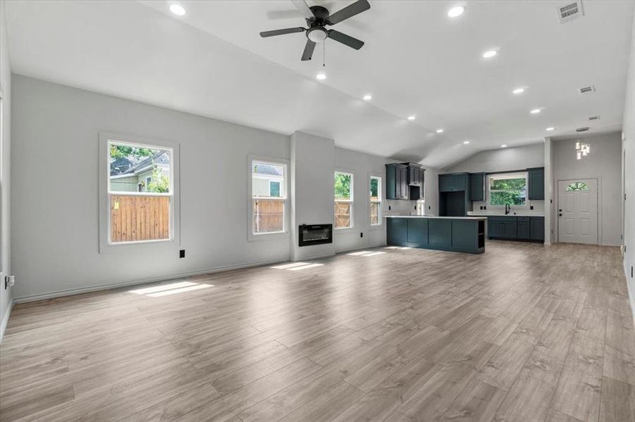 Unfurnished living room with sink, light hardwood / wood-style flooring, ceiling fan, and vaulted ceiling