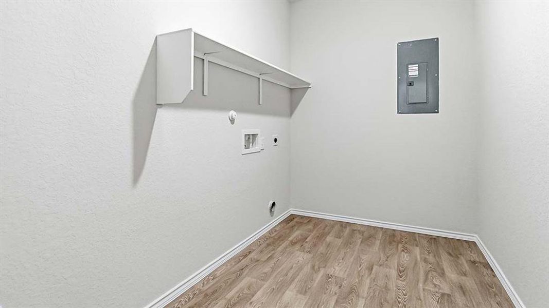 Dedicated utility space featuring wood-finish flooring, white walls, and a built-in wall shelf