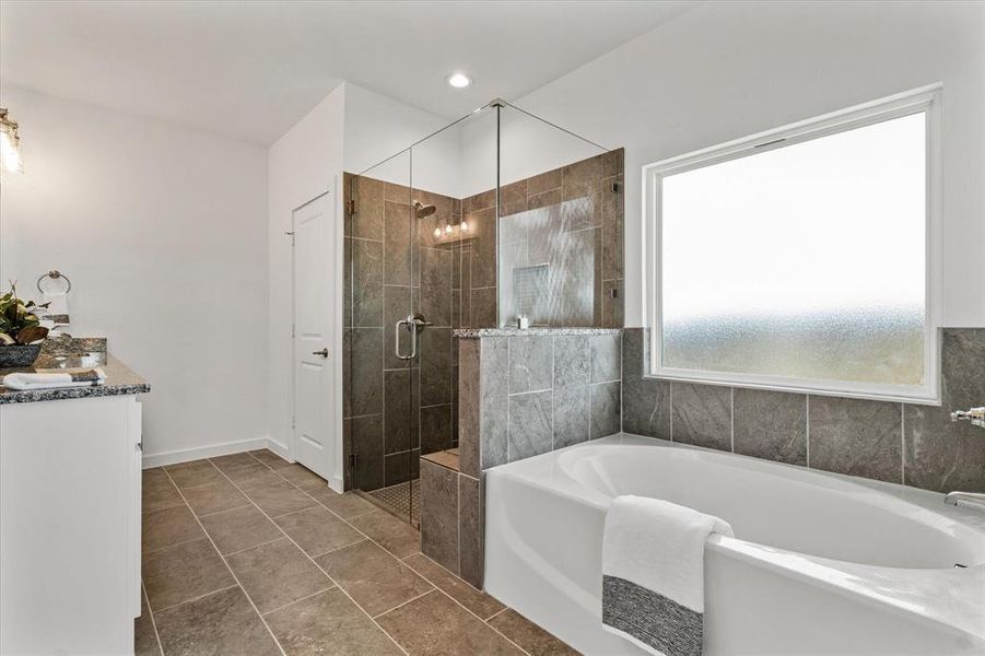 Bathroom featuring tile patterned flooring, vanity, and shower with separate bathtub