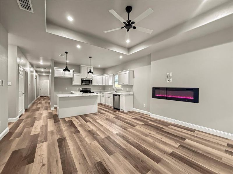 Kitchen with open floor plan, white cabinetry, recessed lighting, ceiling fan, and light wood-style flooring