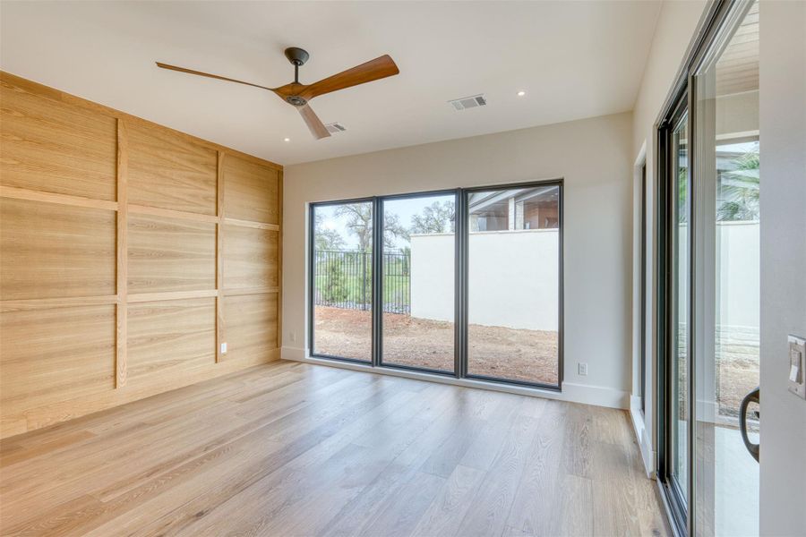 The primary suite is thoughtfully placed on the opposite end of the home from the guest bedrooms.  The bedroom features a wall of windows, oak judges paneling, and a large closet with access to the laundry.