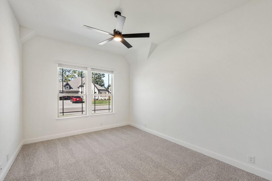 Empty bedroom with vaulted ceiling, ceiling fan, carpet flooring, and double window overlooking neighborhood Empty bedroom with vaulted ceiling, ceiling fan, carpet flooring, and double window overlooking neighborhood