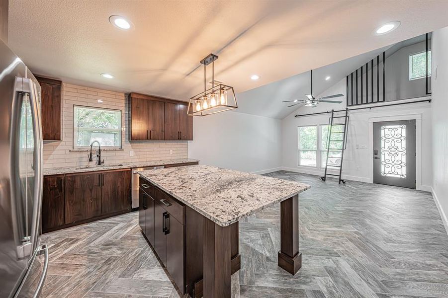 Kitchen featuring decorative backsplash, stainless steel appliances, a kitchen island, dark brown cabinets, and recessed lighting Kitchen featuring decorative backsplash, stainless steel appliances, a kitchen island, dark brown cabinets, and recessed lighting