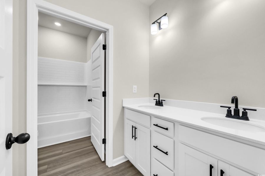 Full bathroom with double vanity and light wood-style floors