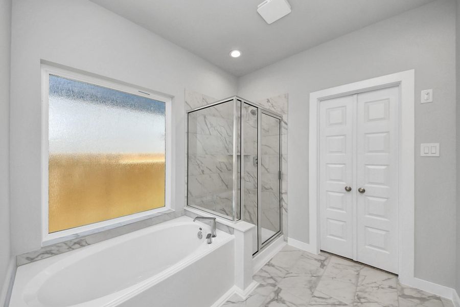 This additional view of the primary bath features a walk-in shower with the tile surround and separate garden tub perfect for soaking after a long day. Sample photo of completed home with similar floor plan. Actual colors and selections may vary.