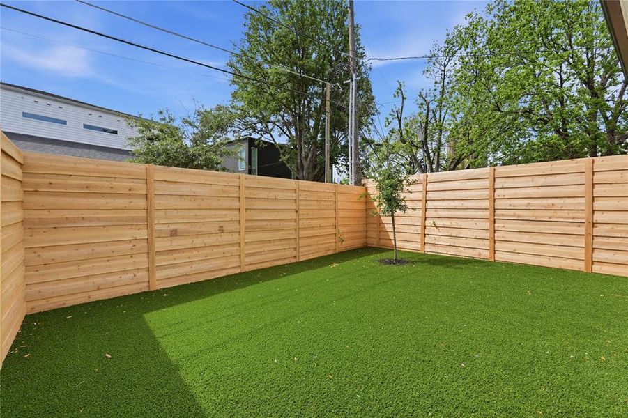 Rear yard featuring artificial turf and a new wood fence