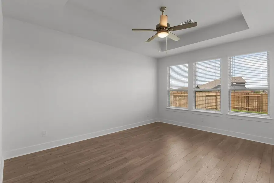 A quiet bedroom, graced with a tray ceiling and light-hued flooring, offers a peaceful retreat.