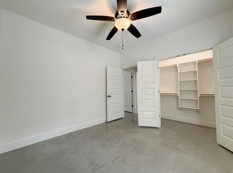 Unfurnished bedroom featuring finished concrete floors and a ceiling fan Unfurnished bedroom featuring finished concrete floors and a ceiling fan