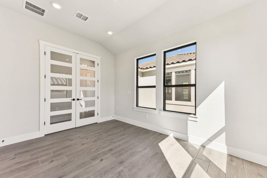 Unfurnished room with recessed lighting, light wood-style flooring, lofted ceiling, and french doors Unfurnished room with recessed lighting, light wood-style flooring, lofted ceiling, and french doors