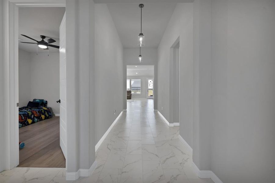 Hallway featuring marble look floor tile and baseboards