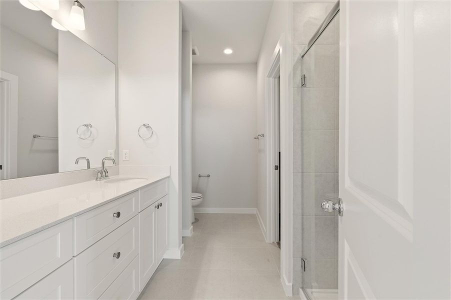 Bathroom featuring a stall shower, vanity, light tile patterned floors, and recessed lighting