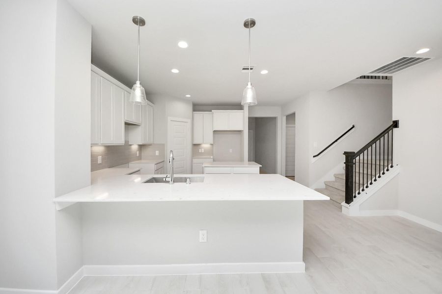 Step into a dream realized with this generously spacious kitchen! A massive granite island takes center stage, complemented by high ceilings and soft-close cabinets. The granite countertops, stainless steel appliances, sleek tile backsplash, and recessed lighting complete the elegant design. Sample photo of completed home with similar floor plan. Actual colors and selections may vary.