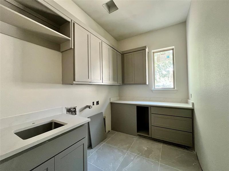 Laundry room featuring sink, washer hookup, light tile patterned flooring, and cabinets