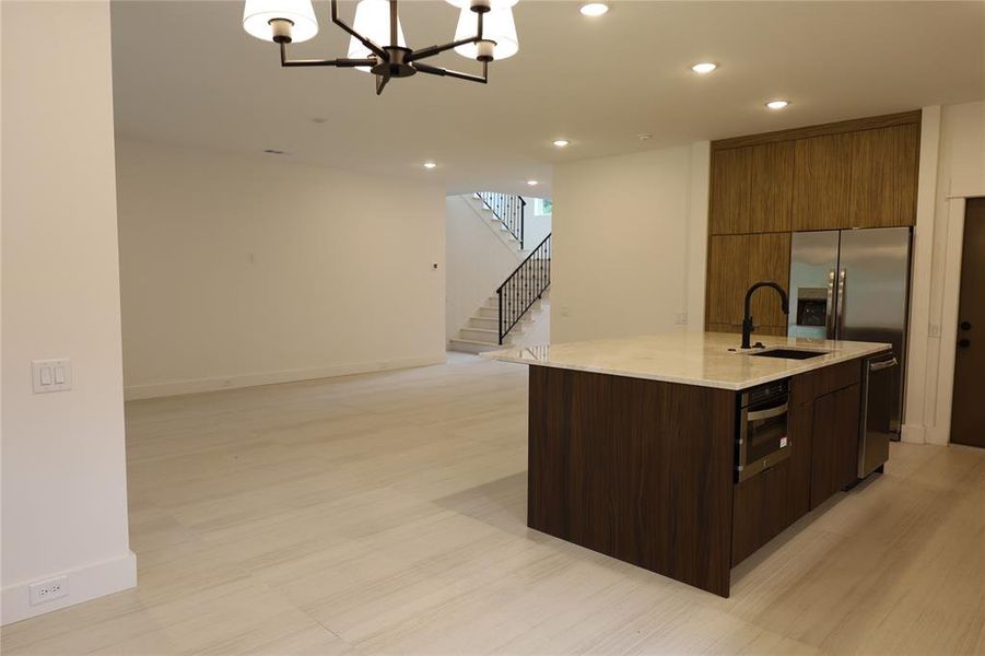 Kitchen with light stone countertops, recessed lighting, open floor plan, modern cabinets, and a kitchen island with sink