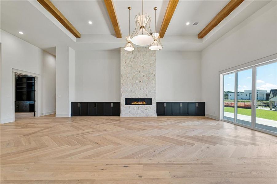 Unfurnished living room with a high ceiling, beamed ceiling, a fireplace, and recessed lighting
