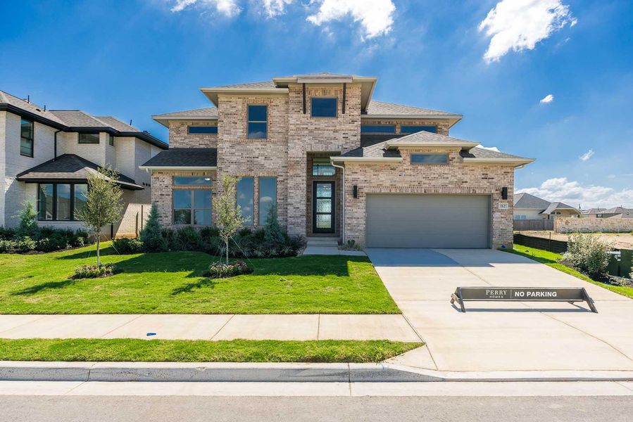 Prairie-style home featuring brick siding, roof with shingles, and concrete driveway