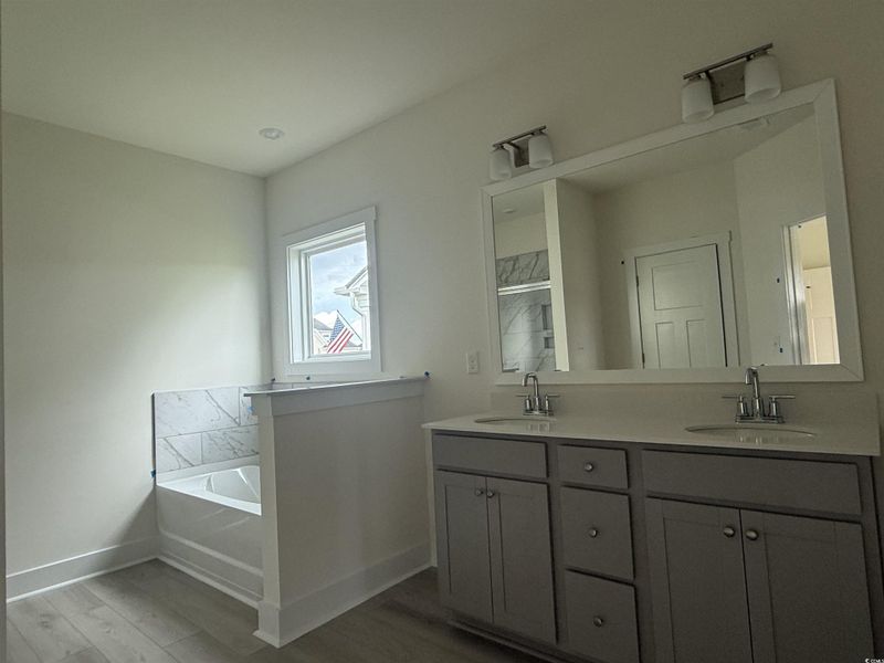Full bath with a bath, double vanity, and wood finished floors