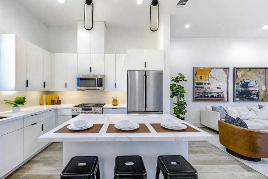 Kitchen features an 11-ft ceiling, quartz island and countertops, stainless-steel GE gas stove, microwave, and dishwasher, plus a stainless-steel sink. Highlights include an uninterrupted backsplash, under-cabinet and pendant lighting, soft-close flat-panel cabinetry with matte black hardware, and a European-style pantry.(Refrigerator shown is virtually staged)