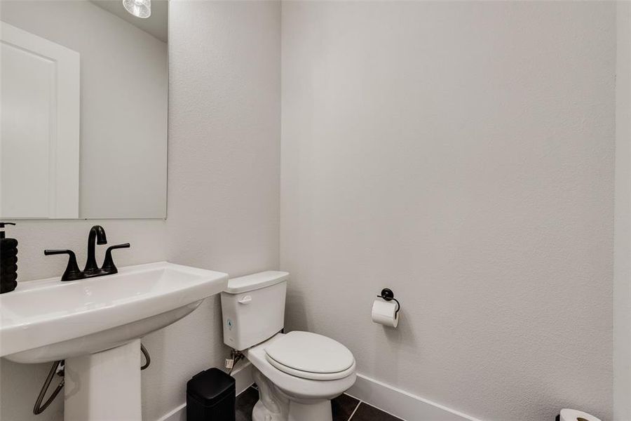 Bathroom with a textured wall and dark tile patterned flooring
