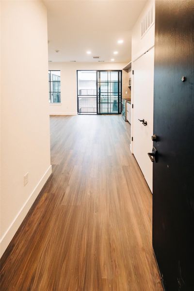 Hall with light wood finished floors and recessed lighting