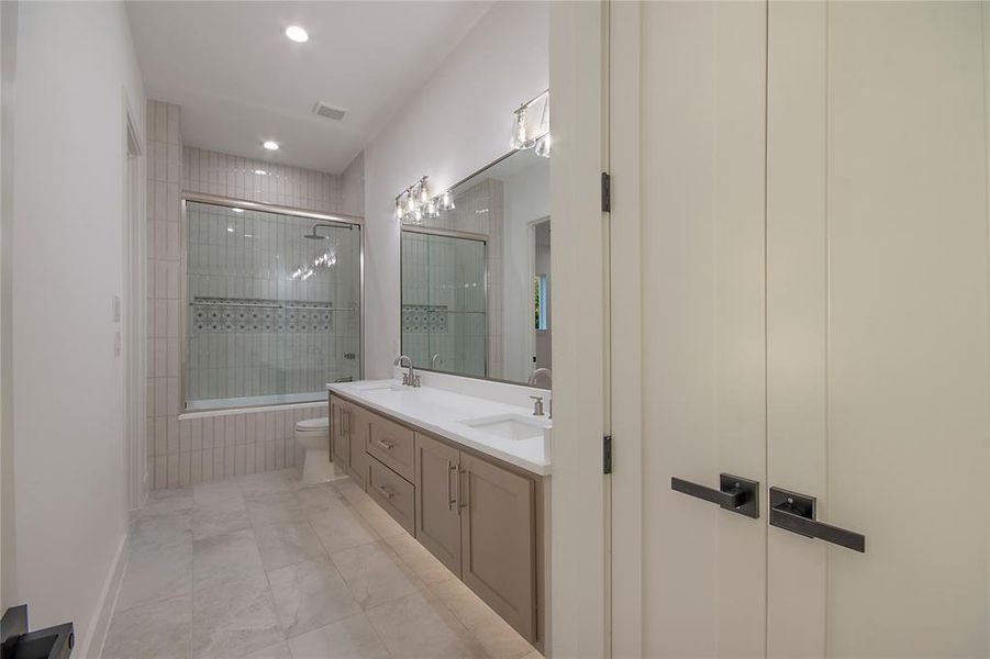 Full bathroom featuring double vanity, light tile patterned floors, and recessed lighting