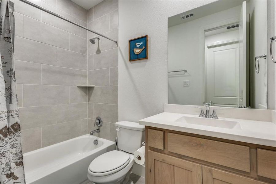 Bathroom with vanity, shower / bath combination with curtain, and a textured wall Bathroom with vanity, shower / bath combination with curtain, and a textured wall